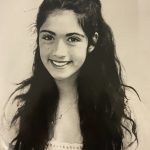 A girl smiling with long black hair.