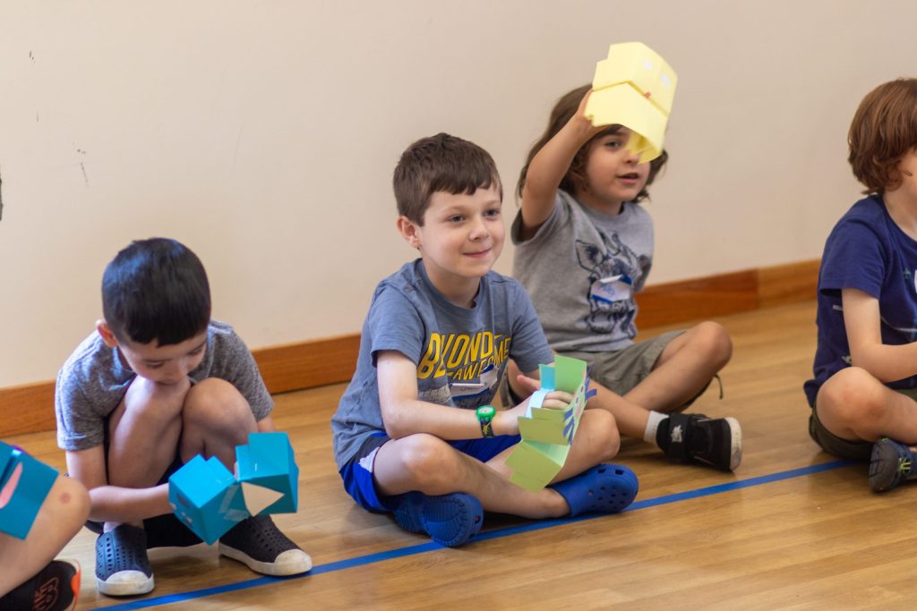 Students sat behind a tapes line waiting patiently to showcase their paper-made cubed puppets.