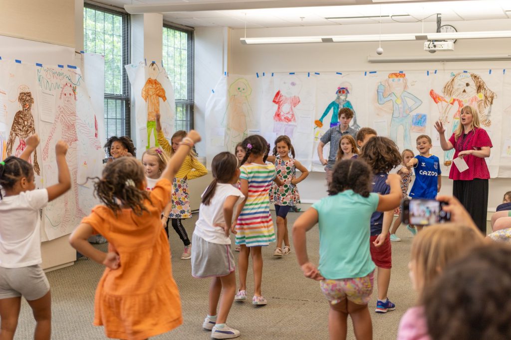 Students in a big group follow the instructions given by the teaching artist.