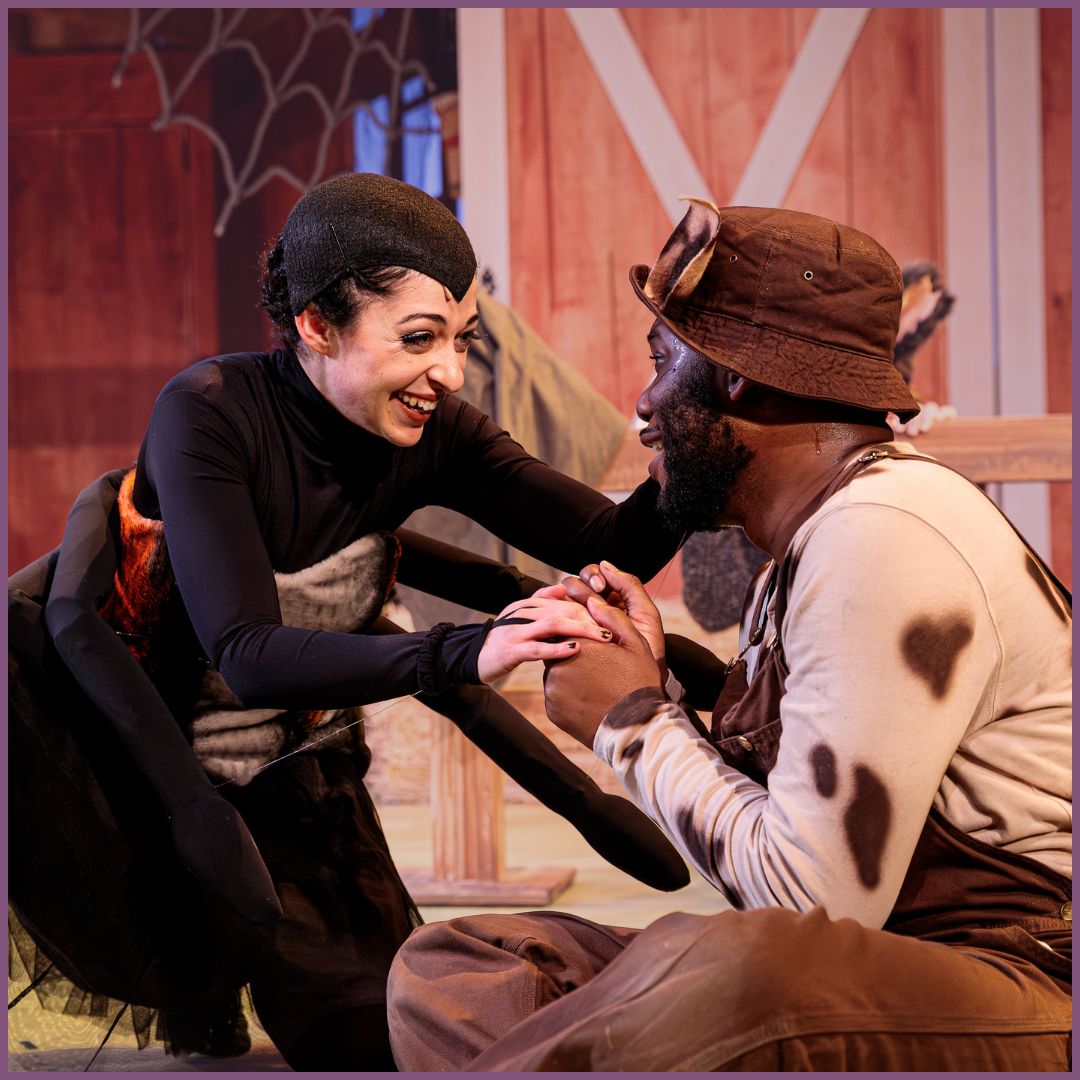 An actor dressed as Charlotte, a spider, holds hands with the actor dressed as Wilbur the pig.