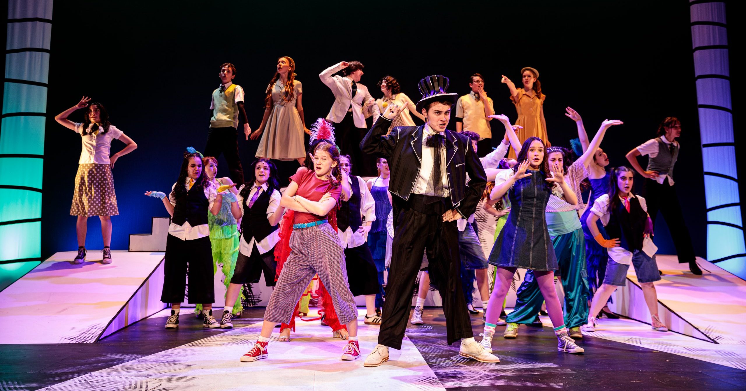 2026seussical-teen-ensemble149 Student performers in brightly colored outfits pose at the end of a musical number