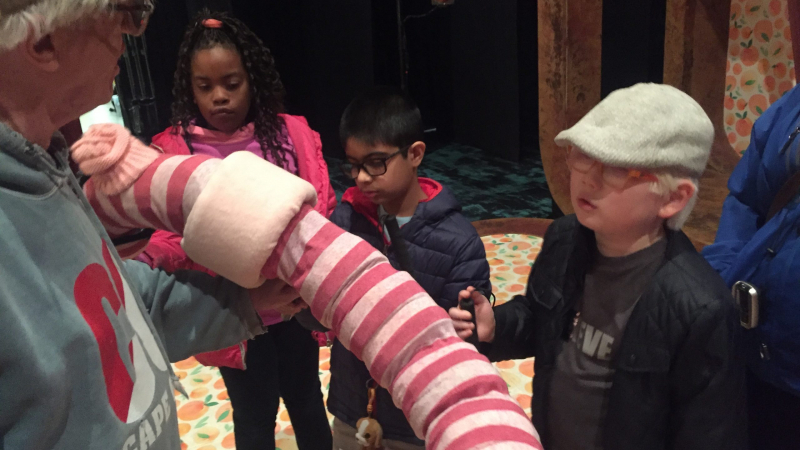Students touch a colorful prop from James and the Giant Peach.
